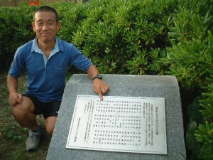 「日本トライアスロン発祥記念銘板」に刻まれた自分の名を指差す北村文俊氏（03年７月撮影）