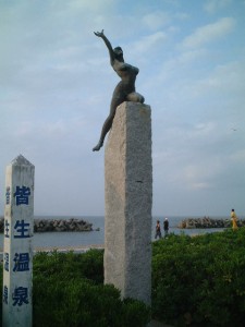 海水浴場の砂浜に立つブロンズ像